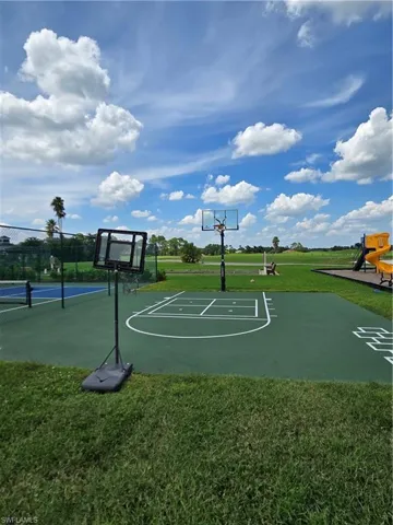 View of basketball court featuring a playground and a yard