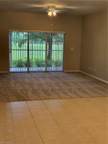 Carpeted spare room featuring ceiling fan and plenty of natural light