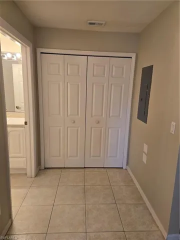 Hall with light tile patterned flooring and electric panel