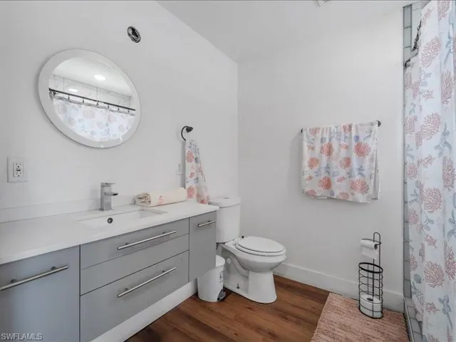 Bathroom featuring a floating vanity with a light gray finish, a white countertop with an integrated sink, and wood-finish flooring