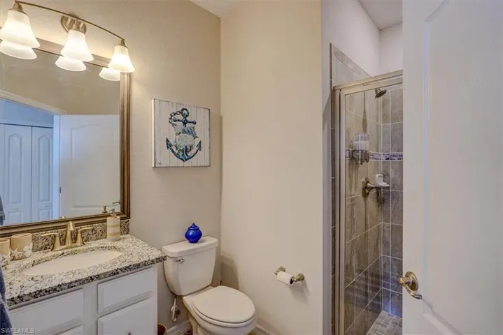 Bathroom with vanity, a shower with shower door, and toilet