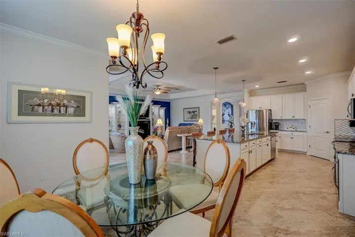 Dining room with crown molding and ceiling fan with notable chandelier