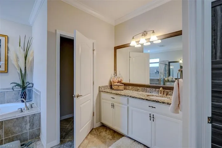 Bathroom with vanity, tile patterned flooring, crown molding, and separate shower and tub