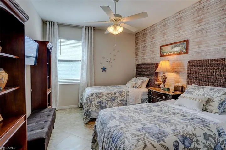 Bedroom with light tile patterned floors, ceiling fan, and wood walls