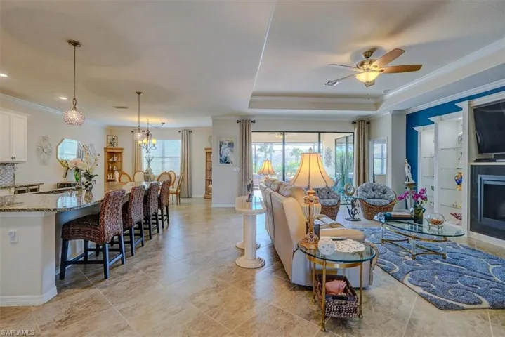 Living room featuring a tray ceiling, crown molding, and ceiling fan with notable chandelier