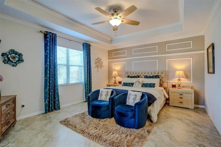 Bedroom with ceiling fan, ornamental molding, a raised ceiling, and light tile patterned floors