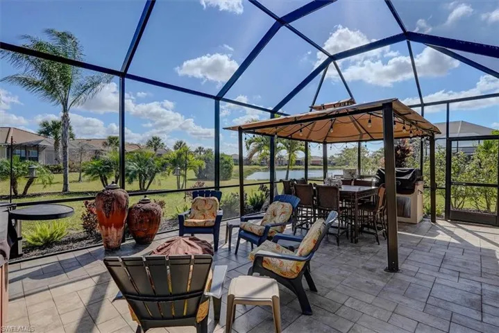 View of patio with a water view, a grill, and a lanai