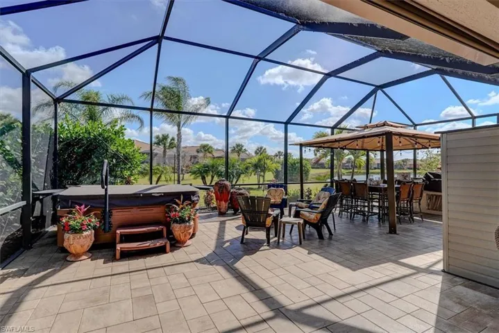 View of patio with a hot tub and glass enclosure