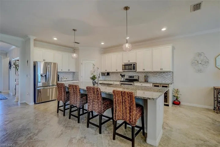 Kitchen featuring stainless steel appliances, an island with sink, a kitchen bar, and white cabinetry
