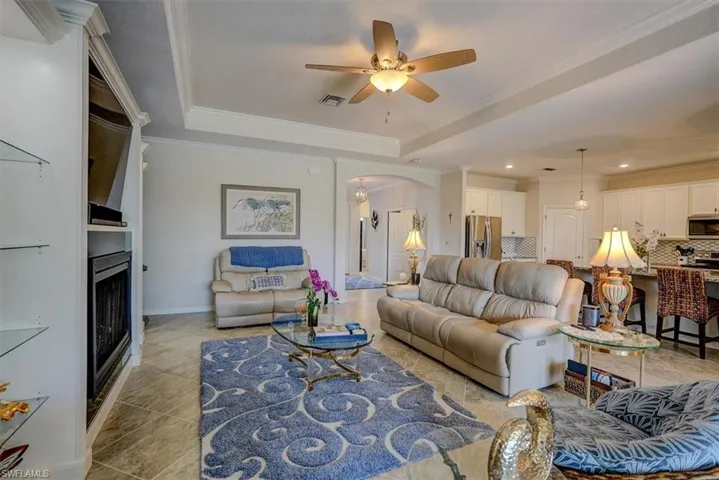 Tiled living room with a raised ceiling, crown molding, and a large fireplace