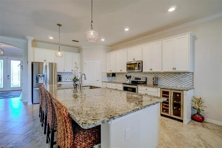 Kitchen featuring an island with sink, stainless steel appliances, beverage cooler, and sink