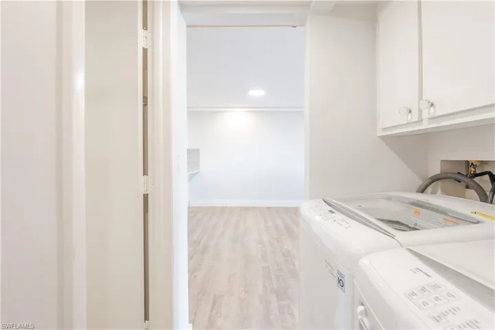 Laundry room with light wood-type flooring, washing machine and clothes dryer, and cabinet space