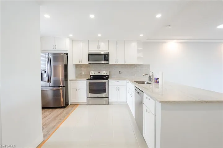 Kitchen with open shelves, stainless steel appliances, recessed lighting, light tile patterned floors, and a peninsula