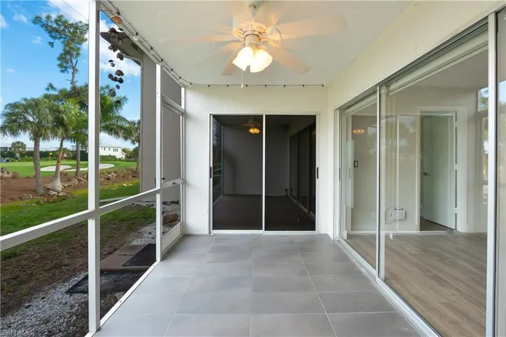 Unfurnished sunroom with ceiling fan and golf course view