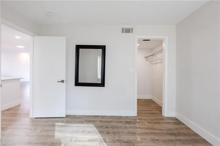 Unfurnished bedroom featuring a spacious closet, light wood-type flooring, recessed lighting, and a textured ceiling