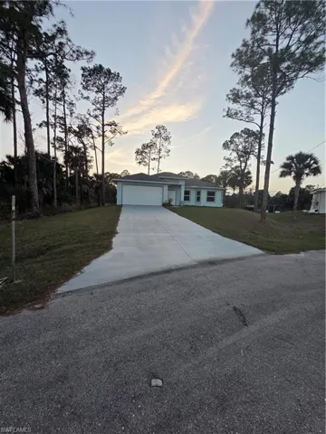 Single story home featuring a yard, concrete driveway, and a garage