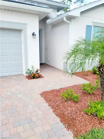 View of exterior entry with stucco siding, a garage, and decorative driveway
