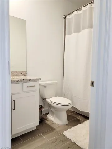 Full bathroom with vanity, wood finish floors, and a shower with shower curtain