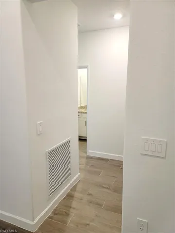 Hall with light wood-type flooring and a textured wall