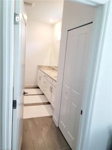 Bathroom featuring double vanity, dark wood-style flooring, recessed lighting, and a closet
