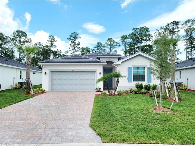 Ranch-style home featuring a front lawn, an attached garage, decorative driveway, and stucco siding
