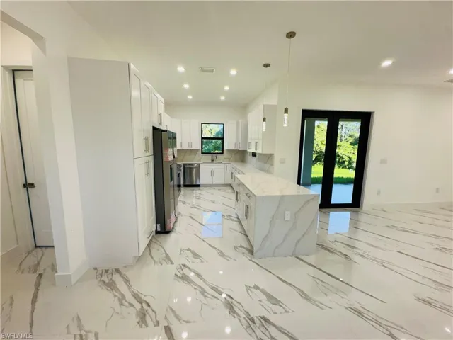 Kitchen featuring white cabinetry, light stone counters, recessed lighting, light marble finish flooring, and stainless steel appliances