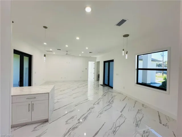 Kitchen with pendant lighting, recessed lighting, open floor plan, light marble finish flooring, and light stone countertops