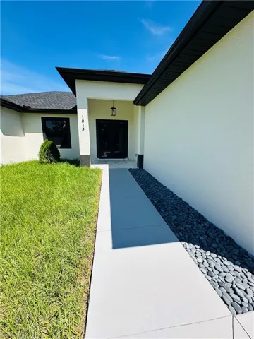 View of exterior entry with stucco siding and a yard