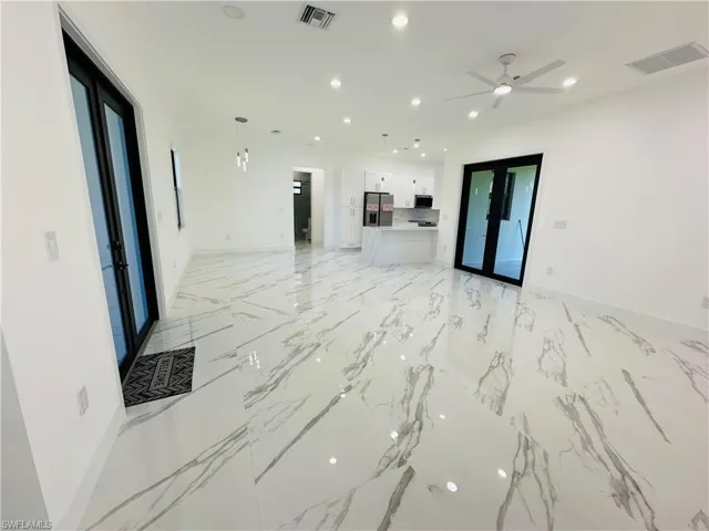 Unfurnished living room featuring recessed lighting, french doors, and light marble finish flooring
