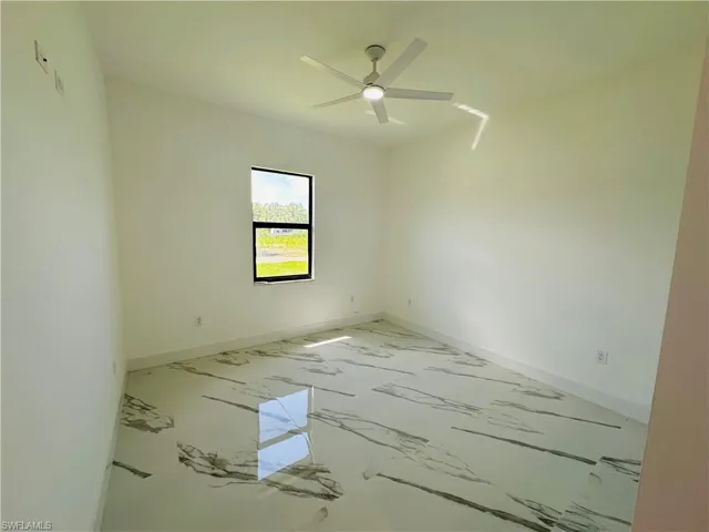Unfurnished room with light marble finish floors and a ceiling fan