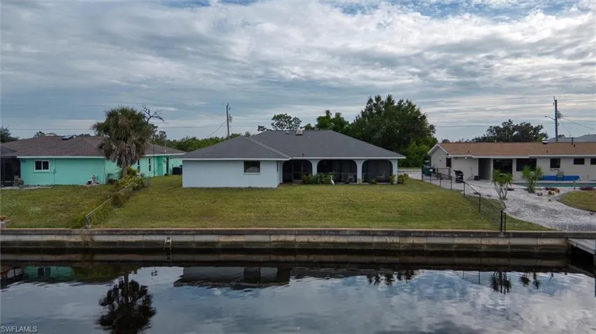 Rear view of property featuring a patio, a lawn, and a water view