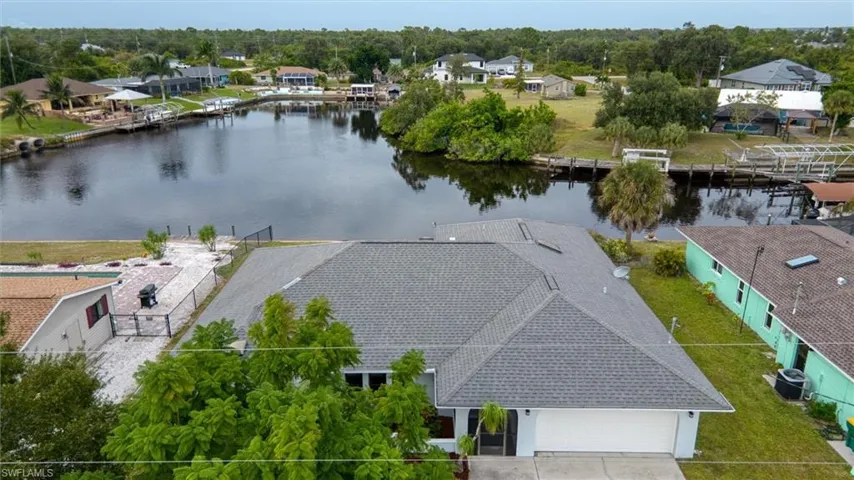 Aerial view of residential area with a nearby body of water and a tree filled landscape