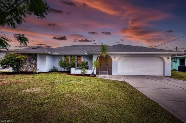 View of front of house featuring stucco siding, a front yard, driveway, and a garage
