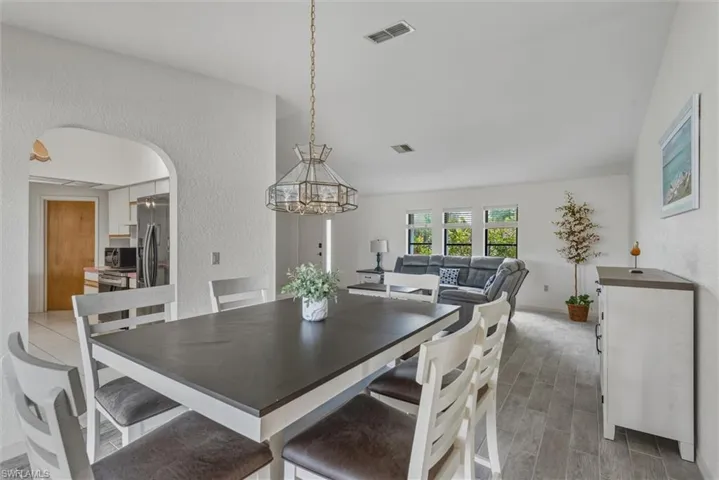 Dining room with a textured wall, arched walkways, wood tiled floors, and a chandelier