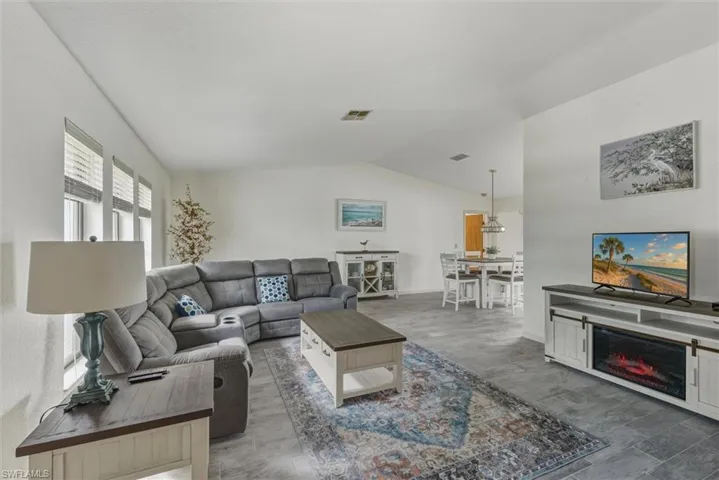 Living room featuring lofted ceiling and a glass covered fireplace