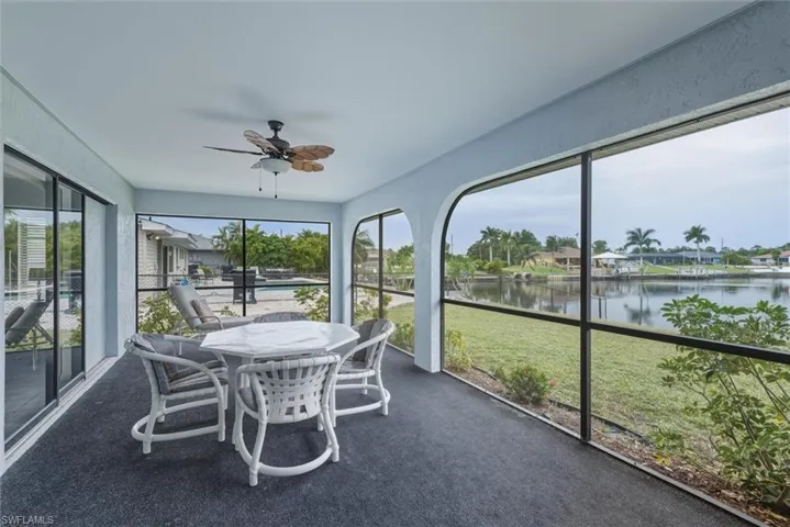 Sunroom with a ceiling fan, a water view, and outdoor dining space