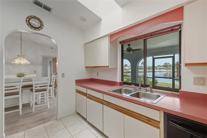 Kitchen with white cabinets, dishwasher, a water view, light countertops, and hanging light fixtures