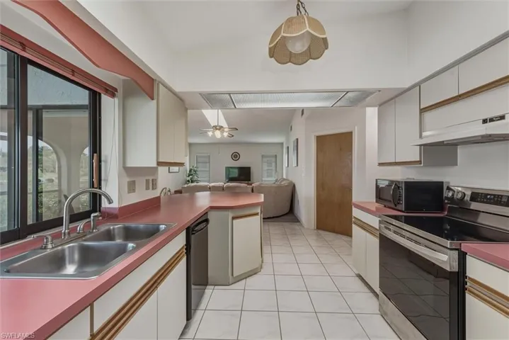 Kitchen featuring black appliances, open floor plan, white cabinets, a ceiling fan, and light tile patterned floors