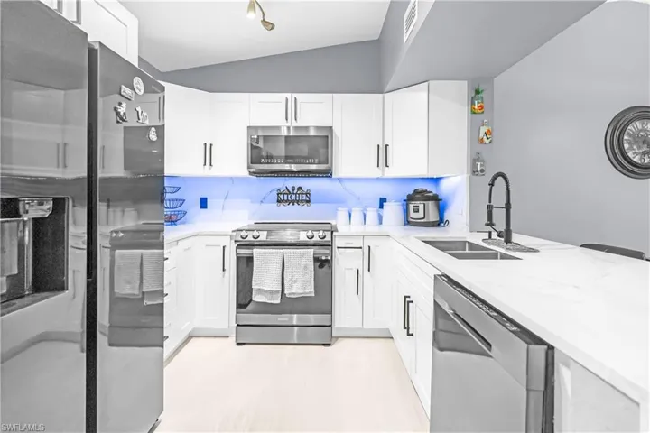 Modern kitchen featuring white shaker cabinetry, stainless steel appliances, and a double basin undermount sink with a matte black faucet
