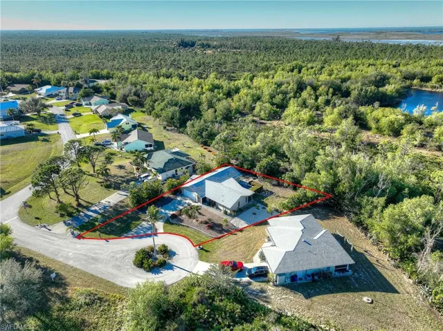 Aerial perspective of suburban area featuring a forest and property boundaries highlighted