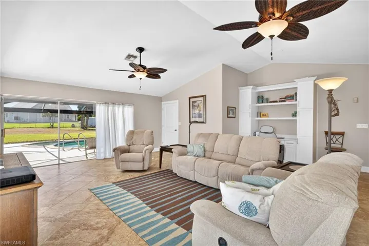Living room with a ceiling fan, lofted ceiling, and a sunroom