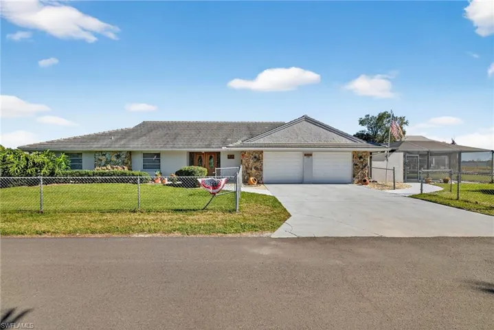 Ranch-style house with a fenced front yard, stone siding, concrete driveway, and a garage