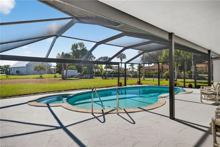 View of swimming pool featuring a lanai, a yard, a sunroom, a patio, and a pool with connected hot tub