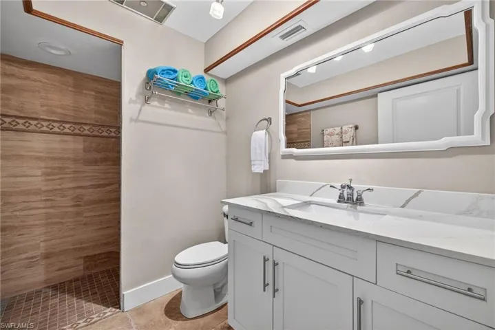 Bathroom with a walk in shower, vanity, and light tile patterned floors