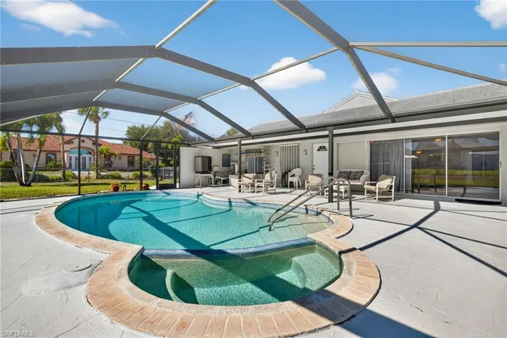 View of swimming pool with a pool with connected hot tub, glass enclosure, a patio area, and a sunroom