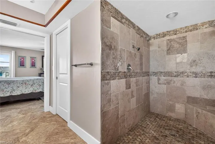 Ensuite bathroom featuring a tile shower and baseboards