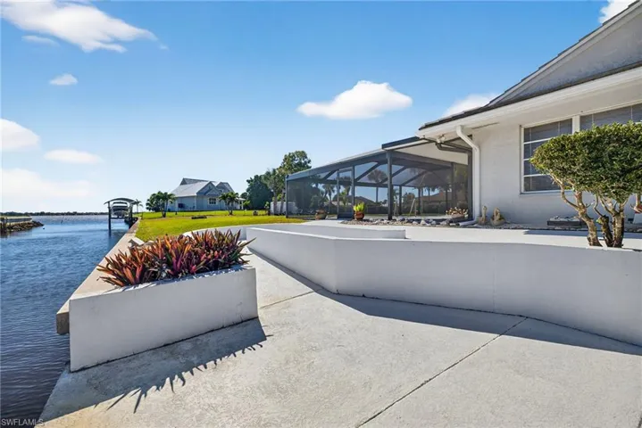 View of patio featuring glass enclosure, a sunroom, and a water view