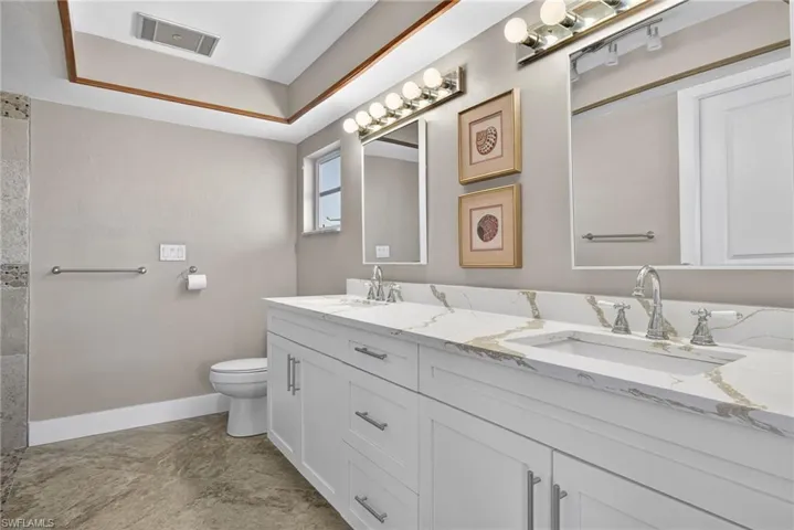 Full bathroom featuring double vanity and toilet