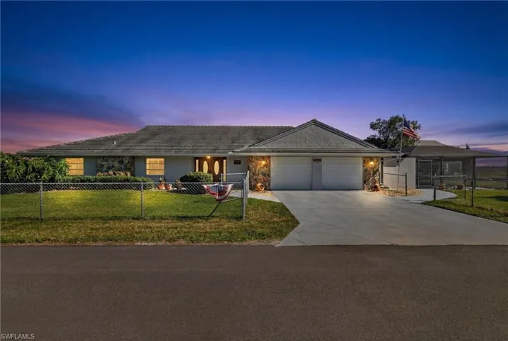 Ranch-style home with a fenced front yard, driveway, an attached garage, and stone siding