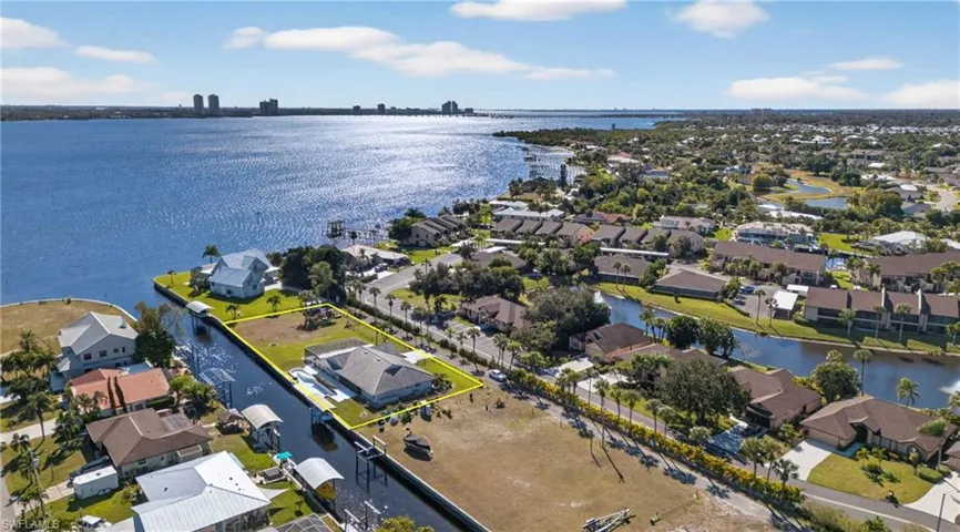 Aerial perspective of suburban area featuring property boundaries highlighted and a nearby body of water